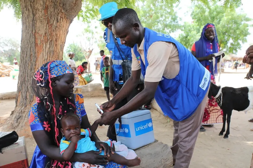 A health worker marks a vaccinated child's finger at an outdoor vaccination point in the Far North Region of Cameroon. 