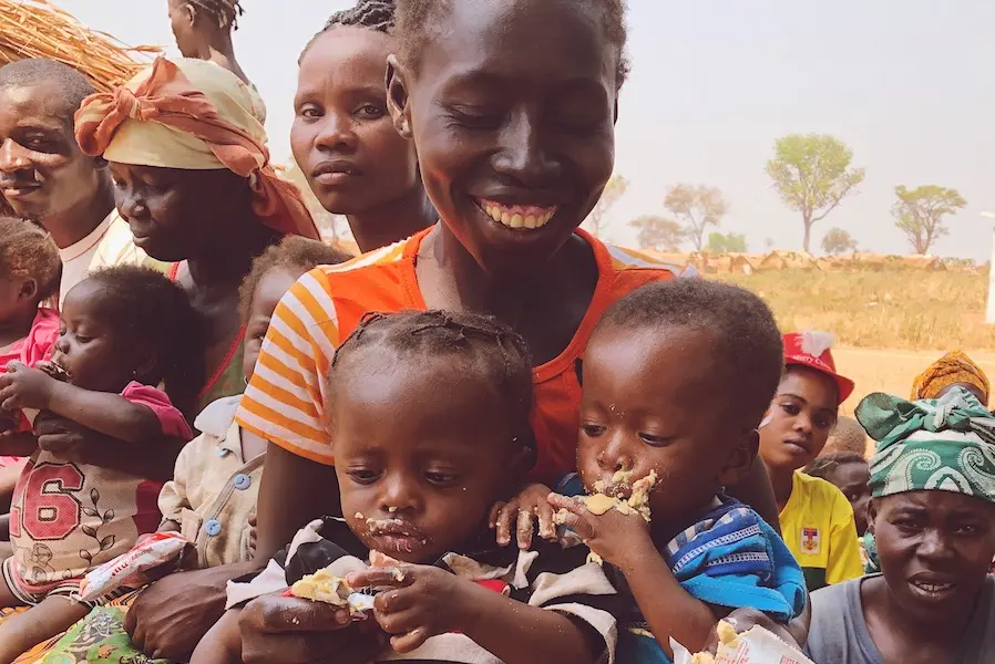 In the Central African Republic, a mother smiles as her twins feed themselves with Plumpy'Nut Ready-to-Use Therapeutic Food at a UNICEF-supported health center. In the Central African Republic, a mother smiles as her twins feed themselves with Plumpy'Nut Ready-to-Use Therapeutic Food at a UNICEF-supported health center.