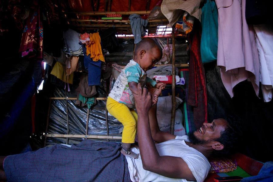Rohingya refugee Saber, 28, plays with his 18-month-old daughter Mobashera Bibi inside their shelter in Burmapara makeshift settlement, Cox's Bazar, Bangladesh in December 2017.