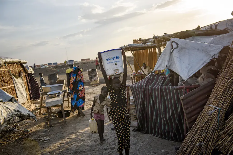 A child carries a bucket filled with water from a water point in the Protection of Civilians (PoC) site in Bentiu, South Sudan, May 2017. A child carries a bucket filled with water from a water point in the Protection of Civilians (PoC) site in Bentiu, South Sudan, May 2017.