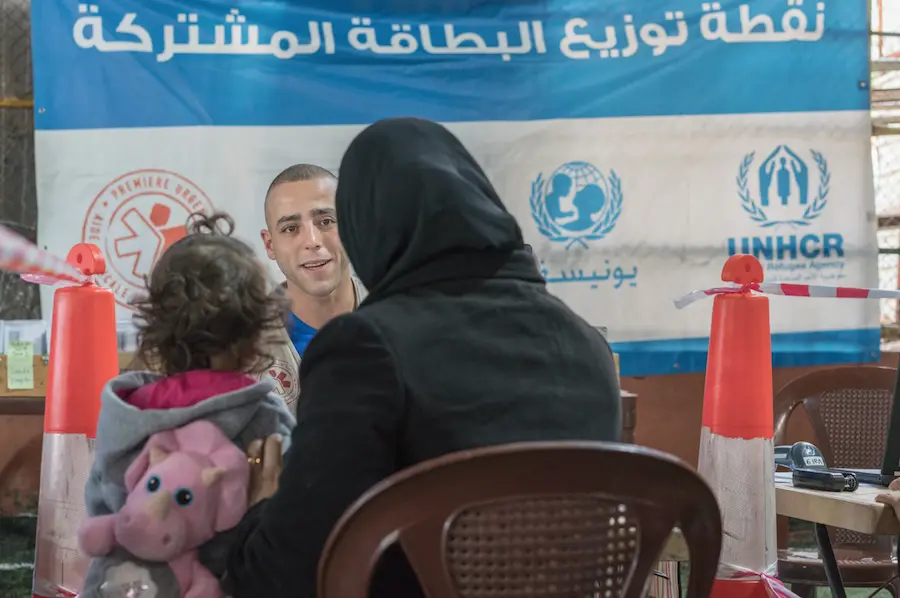 A Syrian mother and child receive their LOUISE common card from an aid worker outside Beirut, Lebanon in January 2018. A Syrian mother and child receive their LOUISE common card from an aid worker outside Beirut, Lebanon in January 2018.