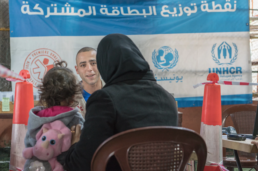 A Syrian mother and child receive their LOUISE common card from an aid worker outside Beirut, Lebanon in January 2018.
