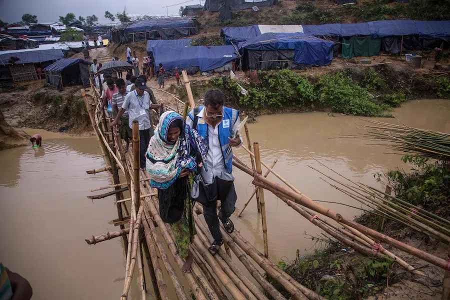 Carryin her newborn granddaughter, Johora, accompanied by a volunteer health worker, crosses a rickety bamboo bridge in the sprawling Kutupalong camp for Rohingya refugees in Cox's Bazar, Bangladesh. Carryin her newborn granddaughter, Johora, accompanied by a volunteer health worker, crosses a rickety bamboo bridge in the sprawling Kutupalong camp for Rohingya refugees in Cox's Bazar, Bangladesh.