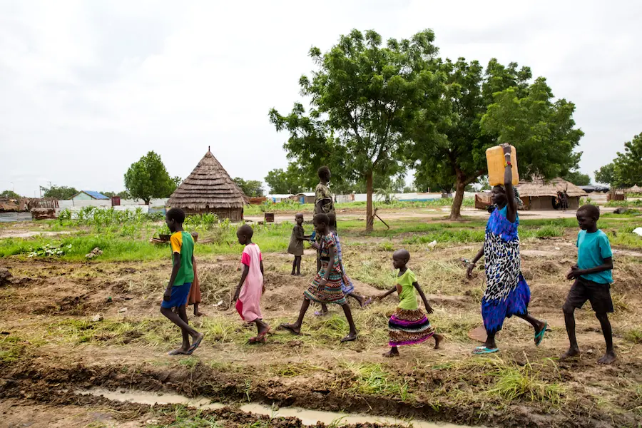 Angelina Nyakuma (second right) walks with children as she carries a jerry can of safe drinking water, drawn from a water pump at the Machakos Primary School, Bentiu, South Sudan, July 2017. Angelina Nyakuma (second right) walks with children as she carries a jerry can of safe drinking water, drawn from a water pump at the Machakos Primary School, Bentiu, South Sudan, July 2017.