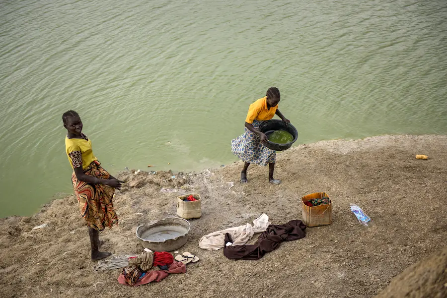 Girls use water from a lake created by pits dug for excavation in the Protection of Civilians site in Bentiu, South Sudan, 28 April 2017. Girls use water from a lake created by pits dug for excavation in the Protection of Civilians site in Bentiu, South Sudan, 28 April 2017.