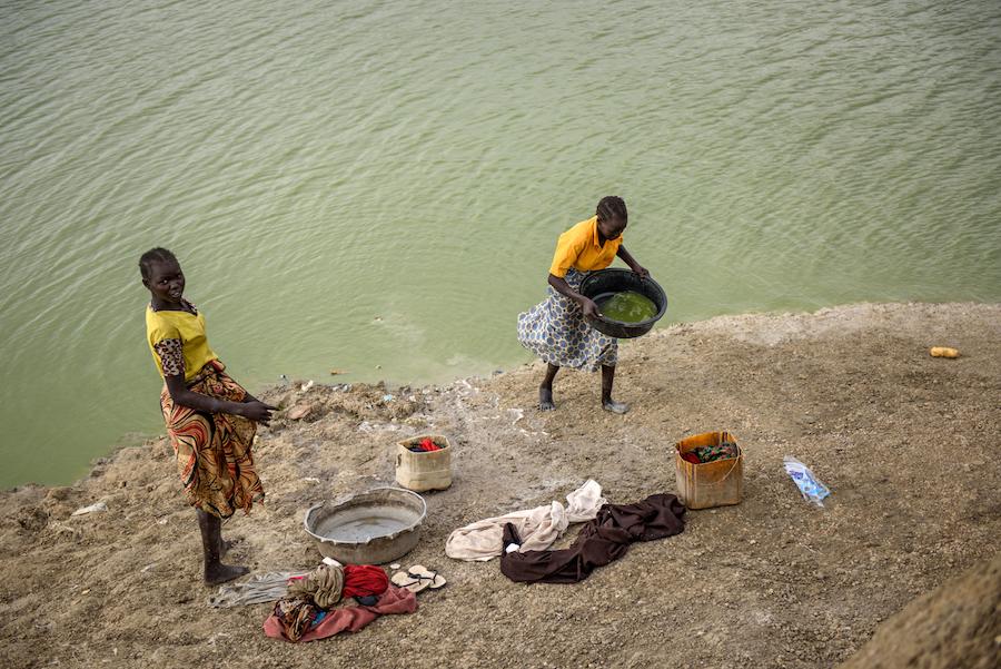 Girls use water from a lake created by pits dug for excavation in the Protection of Civilians site in Bentiu, South Sudan, 28 April 2017. 