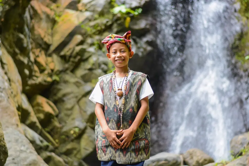 Boy Smiling in front of Waterfall
