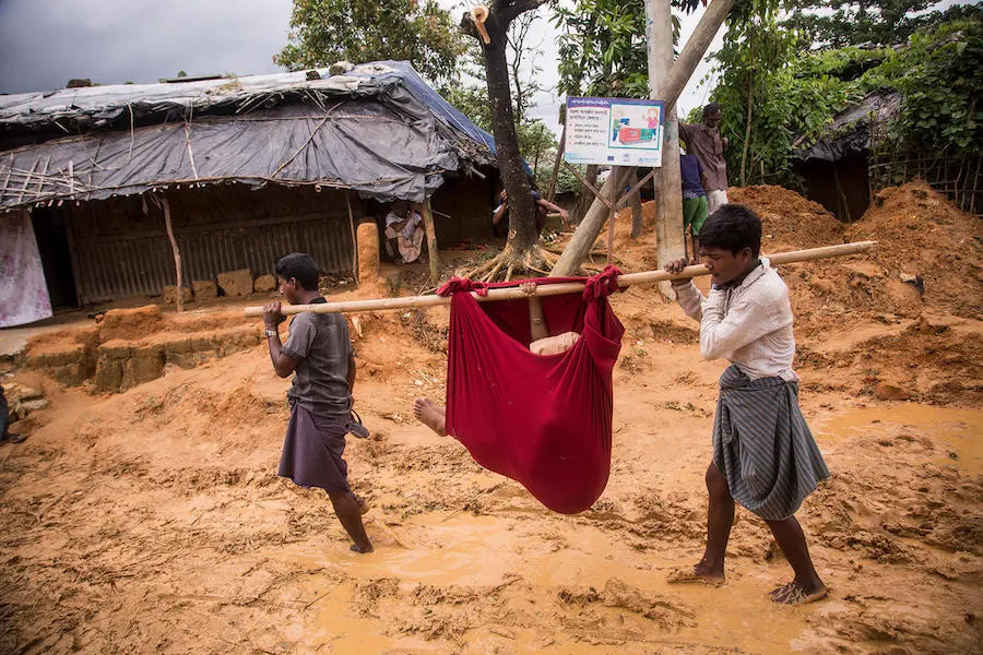 Too weak to walk just days after giving birth, 18-year-old Hazera Begum is carried back to her family's shelter in the Kutupalong camp for Rohingya refugees in Cox's Bazar, Bangladesh. Too weak to walk just days after giving birth, 18-year-old Hazera Begum is carried back to her family's shelter in the Kutupalong camp for Rohingya refugees in Cox's Bazar, Bangladesh.