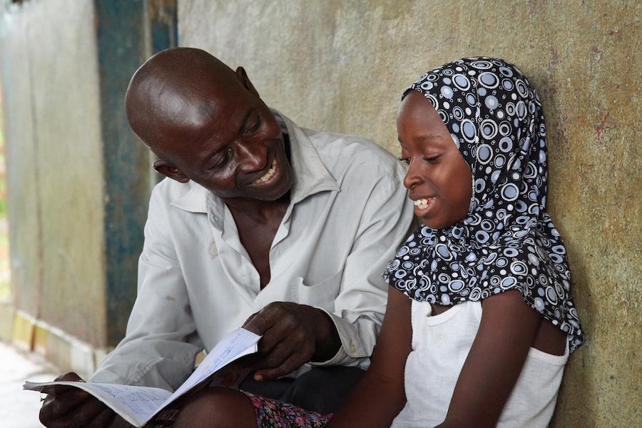 Sulaiman Samura checks the homework of his daughter Fatmata, 10 years old in the the suburb of Hilltop, Freetown, Sierra Leone on May 30, 2017. 