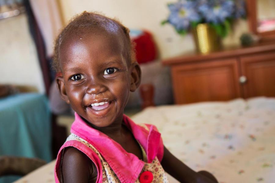 Maria, 2, who was diagnosed with severe acute malnutrition, smiles after her ration of Ready-to-Use Therapeutic Food at her family's home in Juba, South Sudan in November 2017.