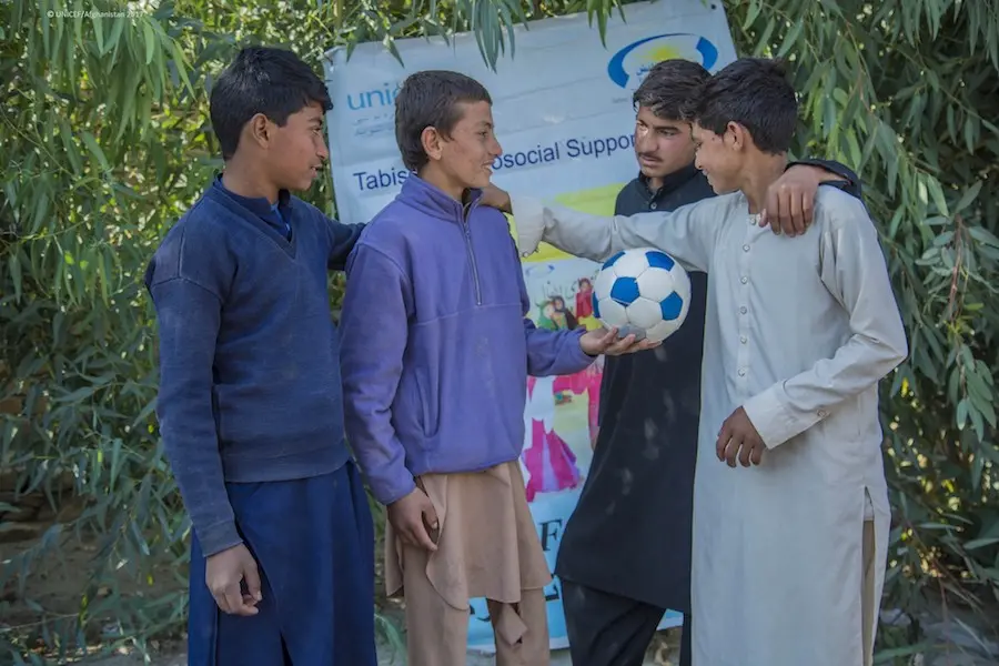 Meeraj, 13, holds a soccer ball and talks with friends at the UNICEF-supported Child-Friendly Space in Ettifaq village, Nangarhar province, Afghanistan in 2017. Meeraj, 13, holds a soccer ball and talks with friends at the UNICEF-supported Child-Friendly Space in Ettifaq village, Nangarhar province, Afghanistan in 2017.