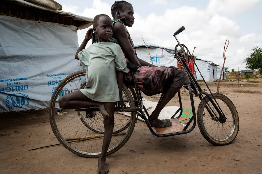 Nyahok, who is physically disabled and relies on a tricycle for mobility, lives in the Kochethey internally displaced persons (IDP) camp, Bentiu, South Sudan, July 2017. Nyahok, who is physically disabled and relies on a tricycle for mobility, lives in the Kochethey internally displaced persons (IDP) camp, Bentiu, South Sudan, July 2017.