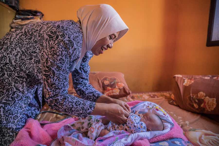 Laticia, 20 days old, is checked by midwife Widyani during a home care visit in Batu, Indonesia. Widyani also delivered the child. 