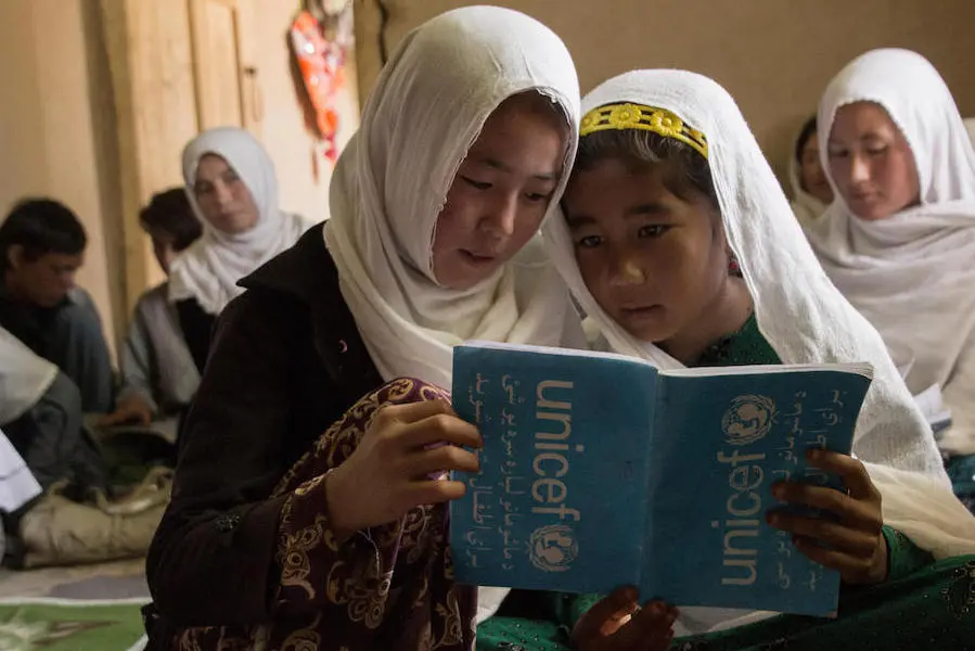 Two girls read from a shared notebook at the UNICEF-supported Accelerated Learning Center in Sharak e Muhajireen village in Nili district, Darikundi province, Afghanistan. Two girls read from a shared notebook at the UNICEF-supported Accelerated Learning Center in Sharak e Muhajireen village in Nili district, Darikundi province, Afghanistan.