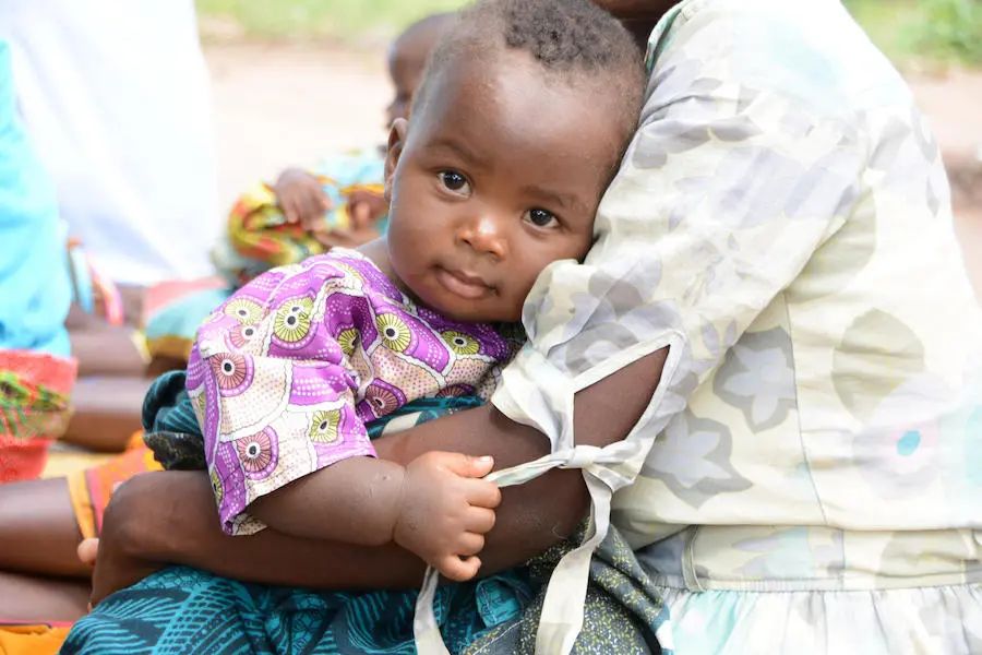 A baby snuggles in her mother's arms outside the UNICEF-supported Mkoko Village Clinic in Phalombe, Malawi in 2018. A baby snuggles in her mother's arms outside the UNICEF-supported Mkoko Village Clinic in Phalombe, Malawi in 2018.