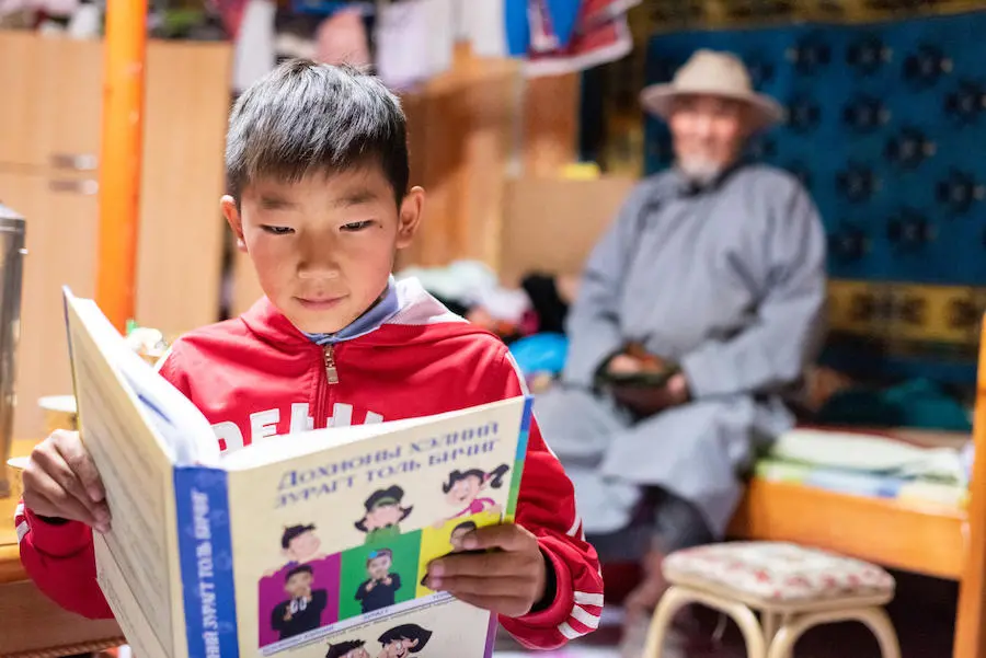 A special needs student reads a book at his house in Altai, Gobi-Altai province, Mongolia in September 2018. UNICEF has developed a sign language book for deaf children. A special needs student reads a book at his house in Altai, Gobi-Altai province, Mongolia in September 2018. UNICEF has developed a sign language book for deaf children.