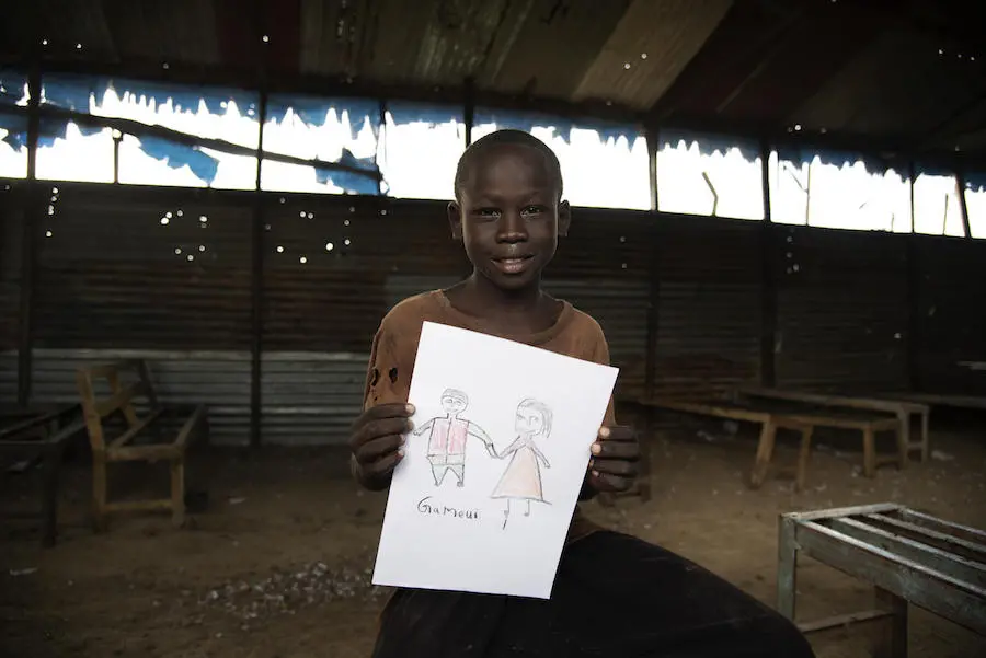 South Sudanese boy Falluoch, 11, holds a drawing of his parents. UNICEF is working to reunite Falluoch, 11, with his parents after they were separated during fighting in Malakal, South Sudan, two years ago.