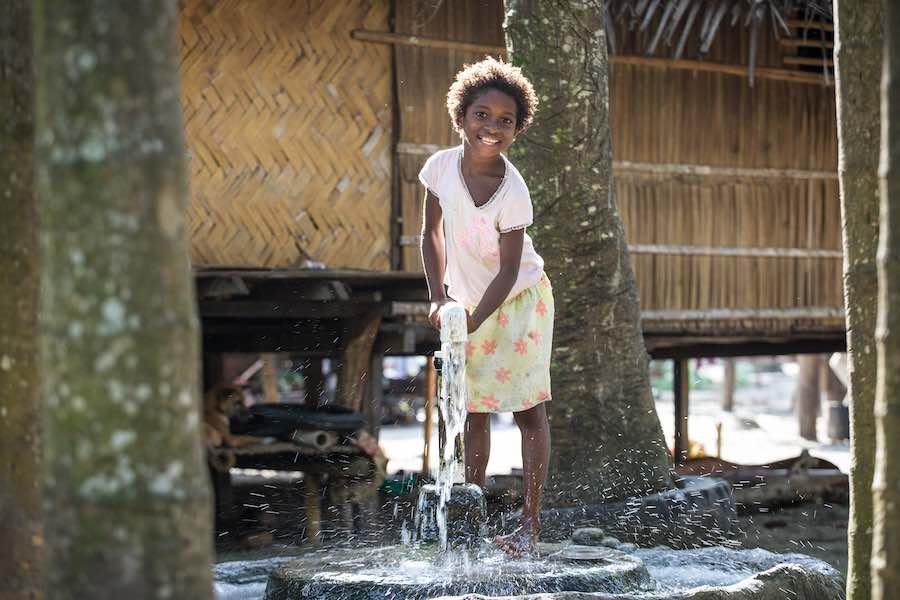 A young girl pumps water from an underground water source at Dugumor Village, Bogia District, Madang Province, Papua New Guinea.