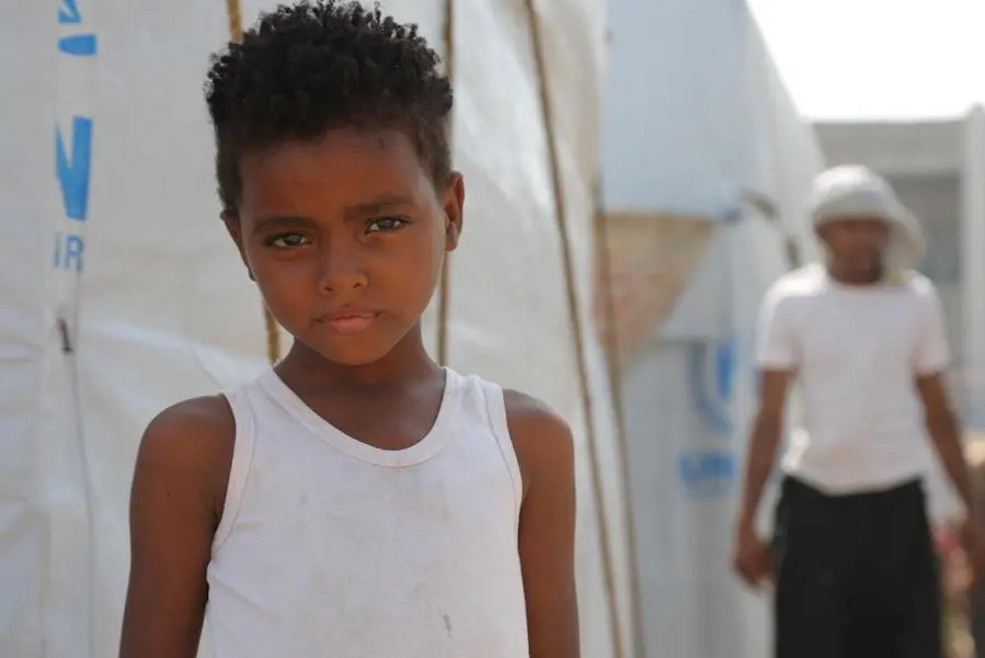 A child stands outside a temporary shelter at a camp for internally displaced persons in Aden, Yemen on December 4, 2018. UNICEF, Yemen, children in conflict