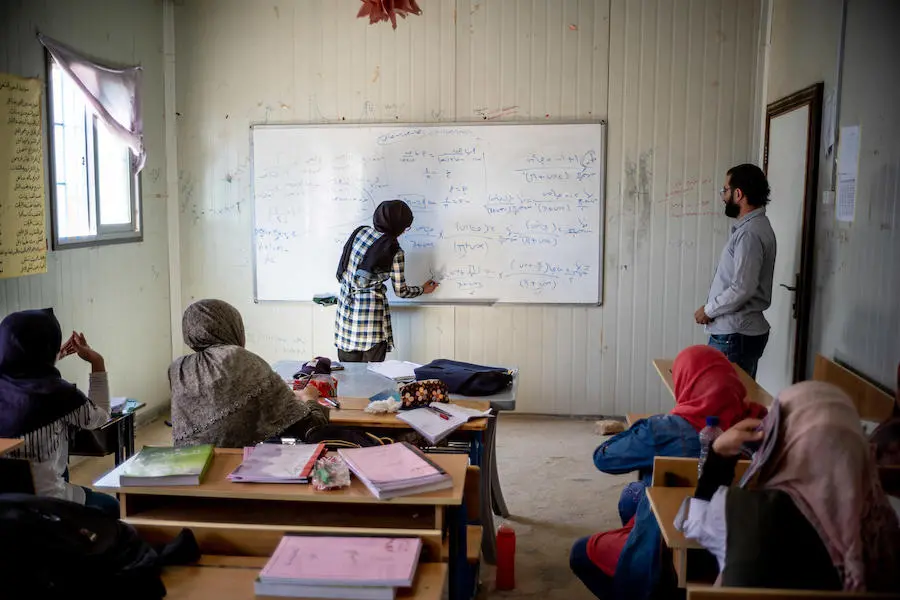 Syrian refugee Bodoor, 17, writes an equation on the white board in class at a UNICEF-supported remedial education center in Azraq refugee camp, Jordan, in 2018.