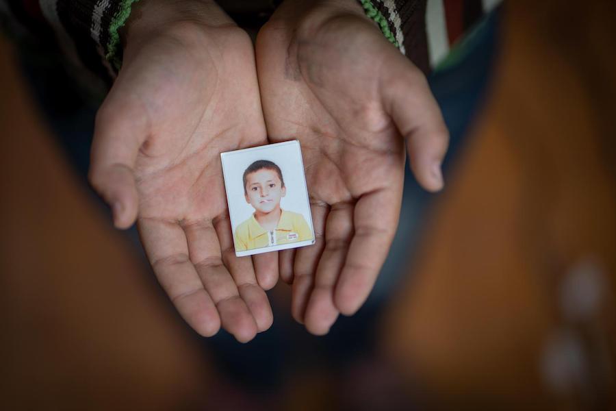 Yahya, 13, holds an old passport photo of himself in Za'atari refugee camp.