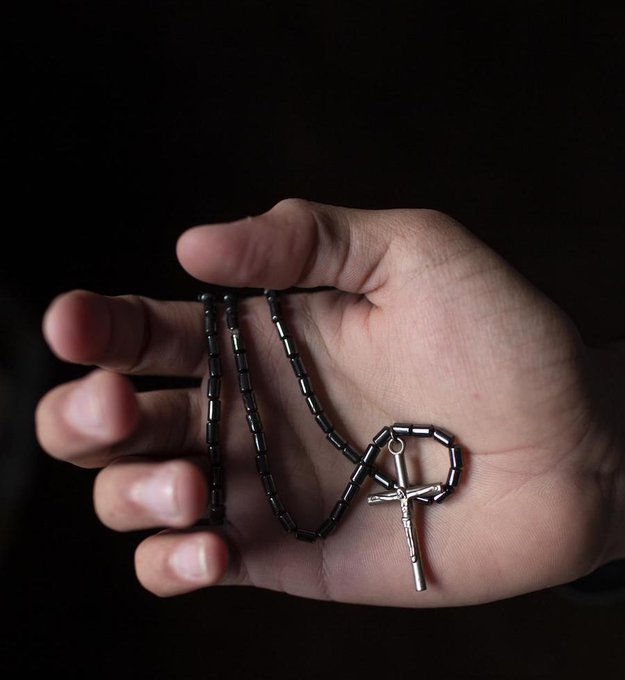 In a Tijuana shelter, Ethan*, 17, holds the rosary his grandmother made for him for his journey with the caravan. He fled gang violence in El Salvador. 