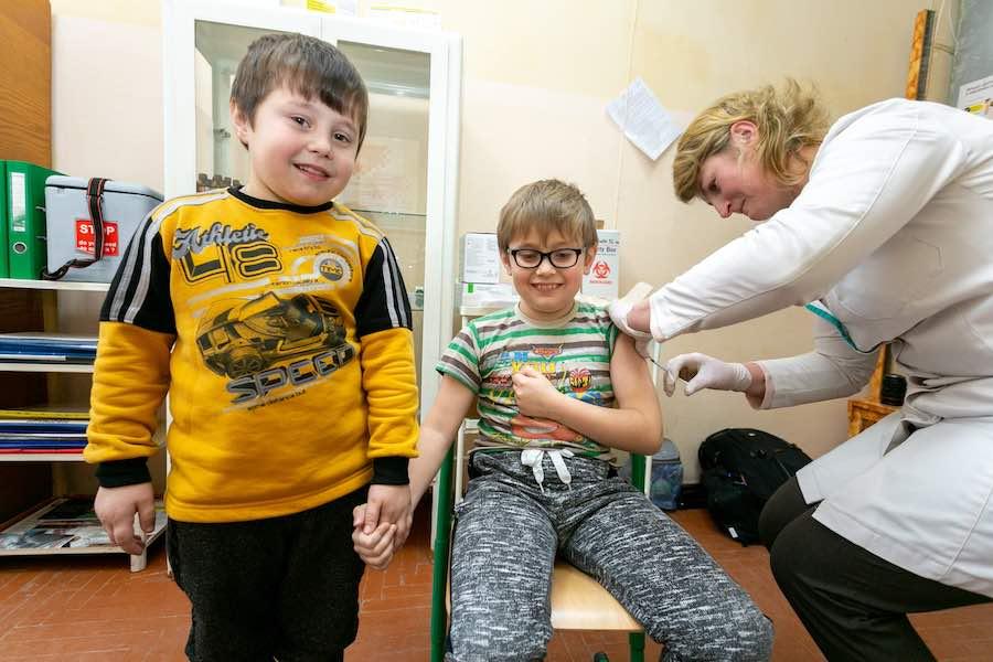 Bohdan Pauk, 6, is holding the hand of his brother Liubomyr, 8, as Liubomyr is receiving his MMR vaccination in the office of a school nurse at Mykolaiv Gymnasium, Lviv region, Western Ukraine. Both boys received their first measles vaccine on 26 February