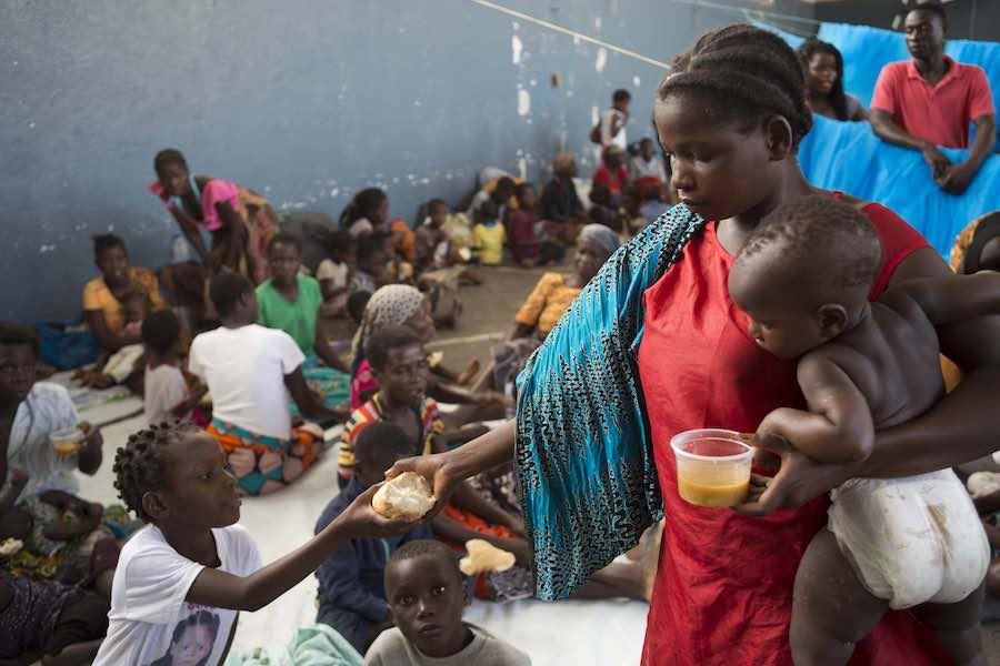 Children receive food from a supermarket chain at the Samora Machel school where they were brought after their homes were destroyed and flooded in Buzi, Mozambique, on Saturday 23 March 2019.