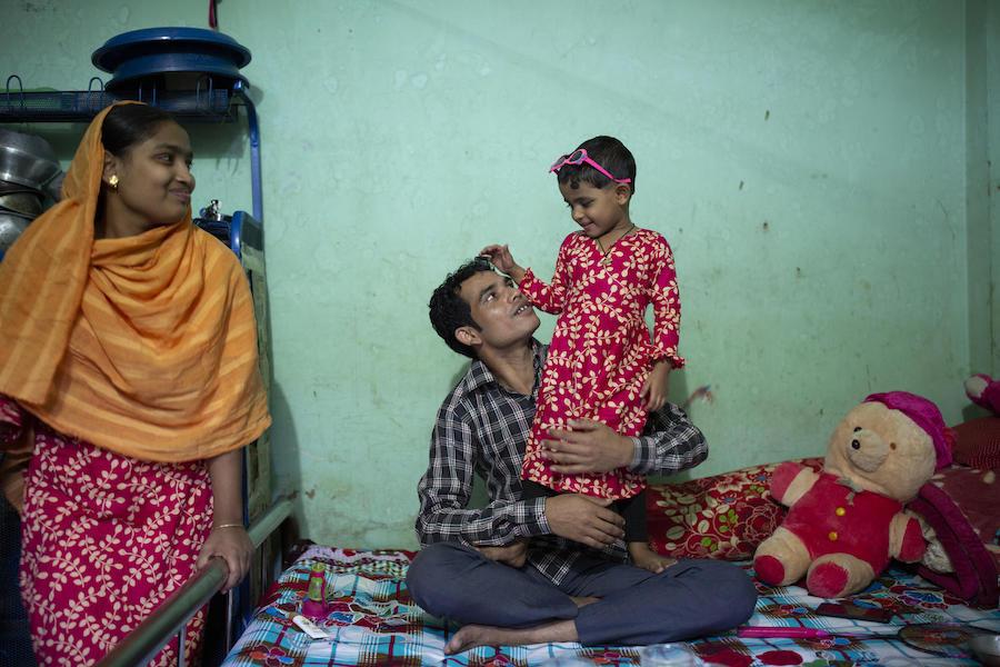 Shumi Akhter, 20, the wife of Jamal Hossain, 26, looks on while he plays with his daughter, Jui, 30 months, at their home near the Northern Tosrifa Group garment factory where they work in Gazipur, outside Dhaka, Bangladesh on December 5, 2018. 