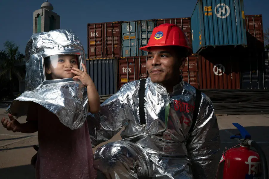 Mohammad Jahirul Islam, 28, dressed in his fire suit, smiles as his daughter Jisha, 3, plays in fire protection gear on the grounds of the Fakir Fashion Ltd. garment factory where he works in Narayangonj, outside Dhaka, Bangladesh on December 10, 2018. Mohammad Jahirul Islam, 28, dressed in his fire suit, smiles as his daughter Jisha, 3, plays in fire protection gear on the grounds of the Fakir Fashion Ltd. garment factory where he works in Narayangonj, outside Dhaka, Bangladesh on December 10, 2018.