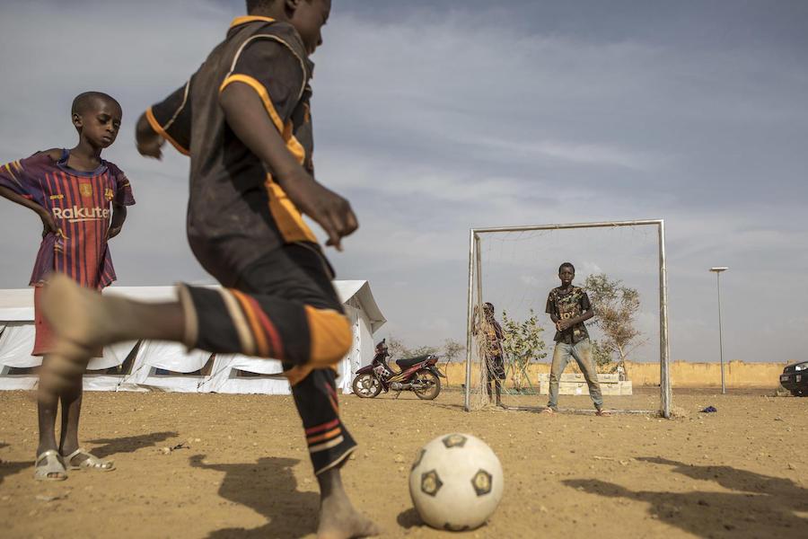 In April 2019, a child kicks a football from a UNICEF-provided recreation kit towards the goal at in the official displacement camp of Socoura set up by UNICEF and partners in the town of Sévaré, Mopti region, in central Mali.