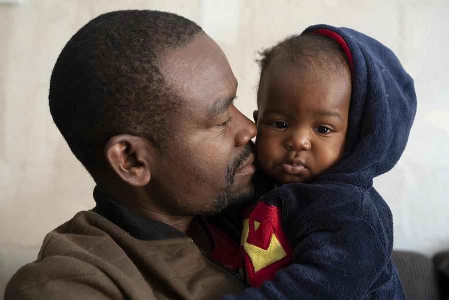 Congolese refugee Dieu-Merci Matala, 44 holds his 7-month-old daughter, Grace, at their apartment in Maitland, Cape Town, South Africa in May 2019.