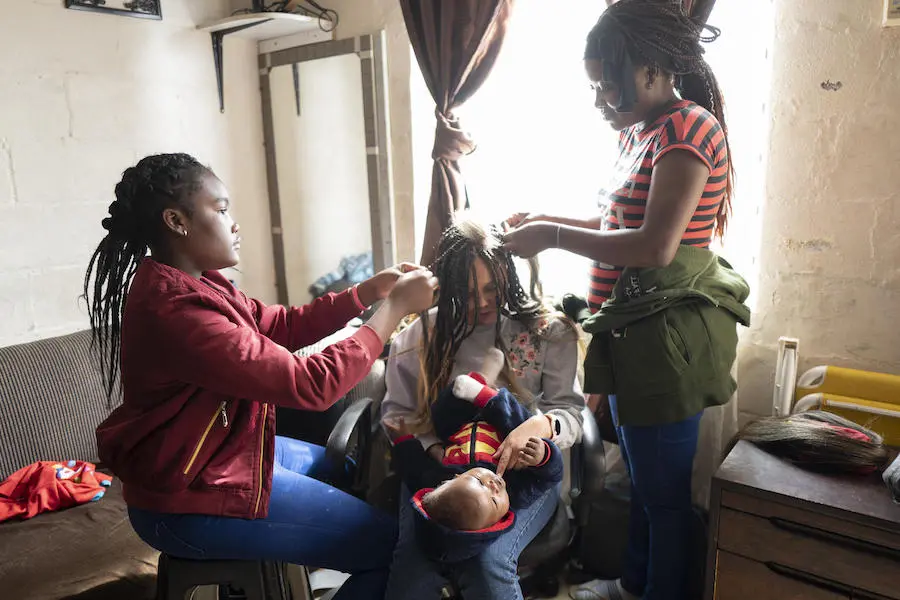 Fortune, left, and her mother, Bibiche, braid a client's hair at the family apartment in Cape Town, South Africa in May 2019. Fortune, left, and her mother, Bibiche, braid a client's hair at the family apartment in Cape Town, South Africa in May 2019.