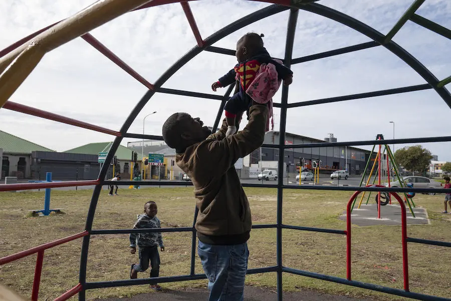 Congolese refugee Dieu-Merci Matala, 44, holds 7-month-old Grace while her older brothers play at a park near the family's apartment in Maitland, Cape Town, South Africa in May 2019. Congolese refugee Dieu-Merci Matala, 44, holds 7-month-old Grace while her older brothers play at a park near the family's apartment in Maitland, Cape Town, South Africa in May 2019.