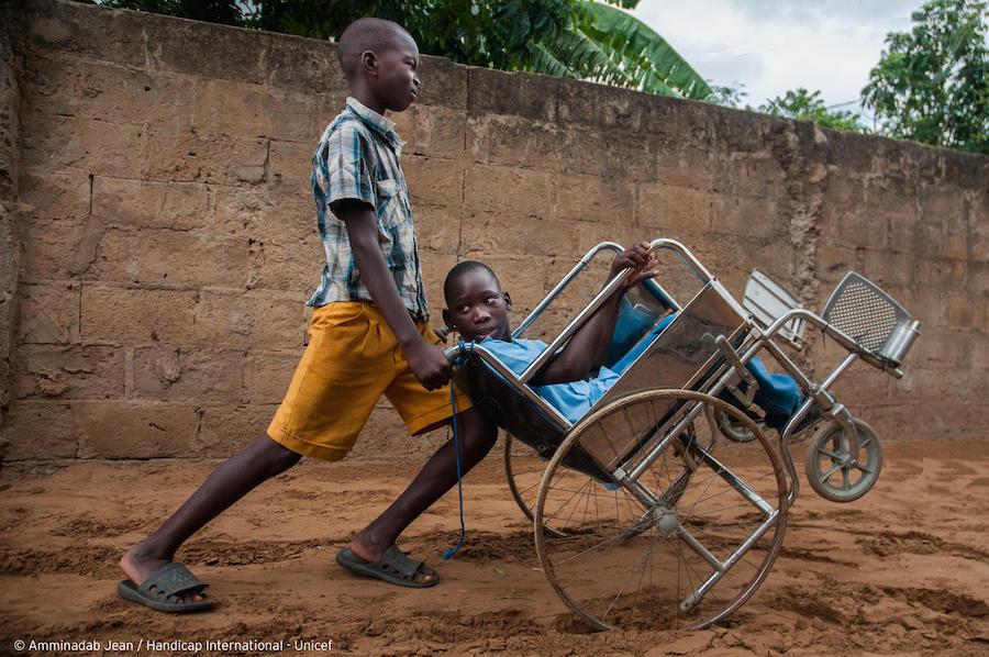 A friend pushes Ilídio, 11, in his wheelchair so he doesn't have to stay home in Mozambique in July, 2019. 