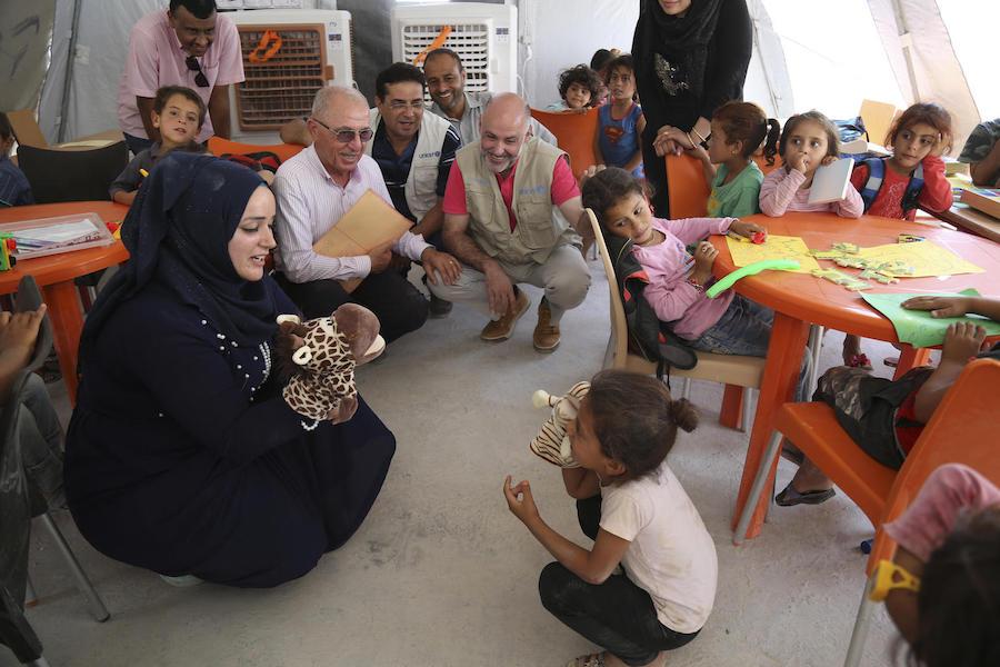 In July 2019, UNICEF Syria Representative Fran Esquiza (in red shirt) and colleagues watches as a UNICEF-supported social worker and a child perform a puppet show in Al-Hol camp in northeastern Syria. 