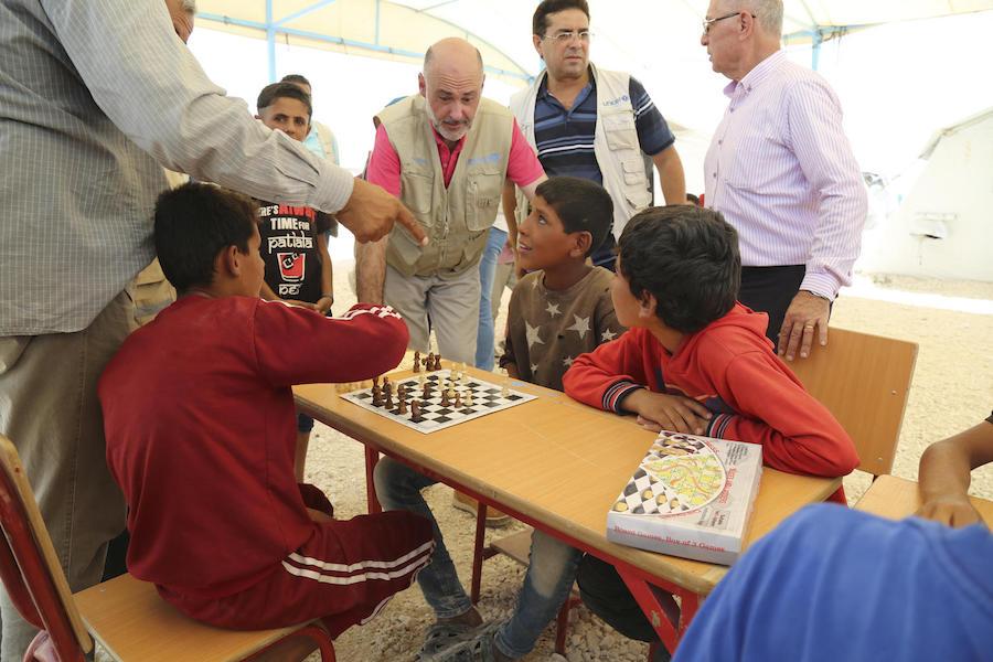 UNICEF Syria Representative Fran Aquiza (center) chats with children playing chess at a UNICEF-supported psychosocial support center in Al-Hol camp, northeastern Syria, in July 2019.