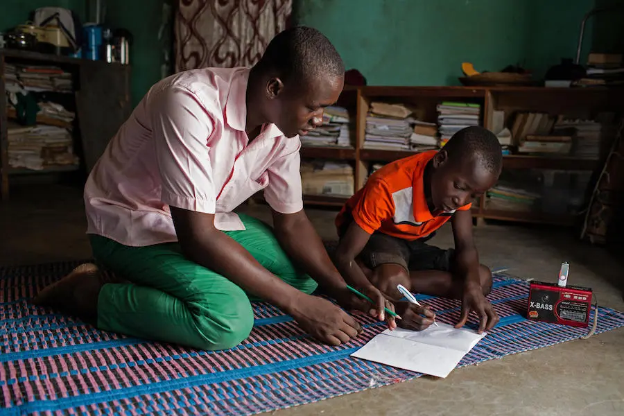 Abdoulaye, 23, a radio school facilitator, guides Hussaini, 14, through lessons broadcast by a UNICEF-supported "radio school" in Dori, Burkina Faso. Abdoulaye, 23, a radio school facilitator, guides Hussaini, 14, through lessons broadcast by a UNICEF-supported "radio school" in Dori, Burkina Faso.