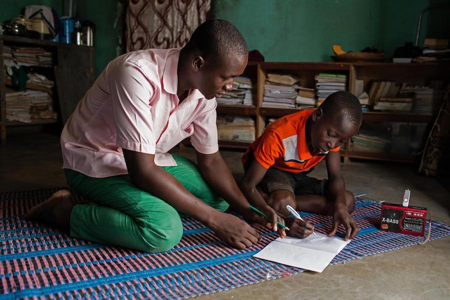 Abdoulaye, 23, a radio school facilitator, guides Hussaini, 14, through lessons broadcast by a UNICEF-supported "radio school" in Dori, Burkina Faso.