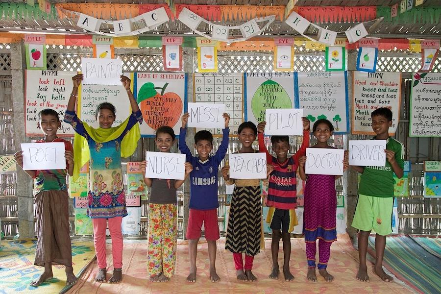 Rohingya refugee children attending UNICEF-supported learning centers in Cox's Bazar, Bangladesh hold signs sharing their hopes for the future. 