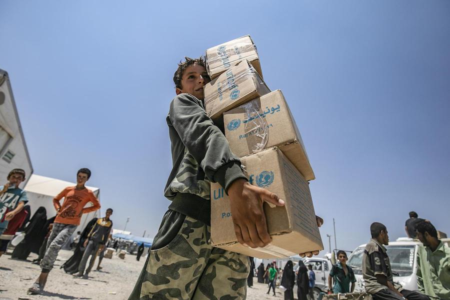 On July 22, 2019 in the Syrian Arab Repubic, a young boy collects a UNICEF-supported summer clothing kit at a refugee camp in Al, south of Hassakeh City. 