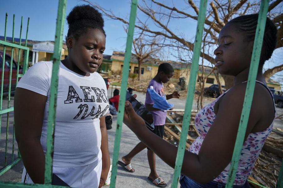 On September 8, 2019 in the Bahamas, Metory, 16, (right) speaks to her younger sister, Brianna, 14, outside the Central Abaco Primary School, a temporary shelter in Marsh Harbour.