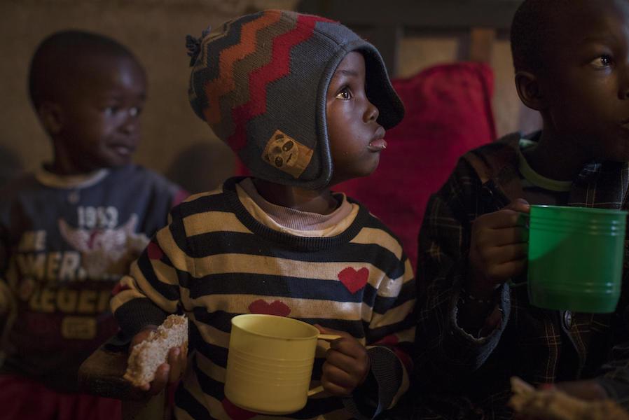 On 28 September 2020 in Kenya, Chris Omondi (center), 7, drinks water while having breakfast with his siblings in their home in Kibera, the largest informal settlement in Nairobi.