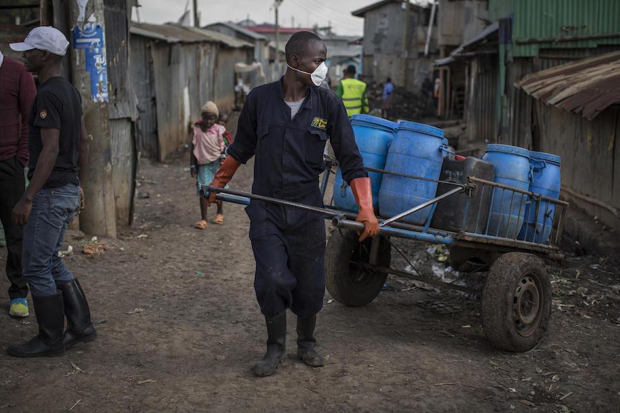 On 1 October 2020 in Kenya, Wiseman Jirungu (center), 26, a Sanergy sanitation employee, collects waste from, and cleans, Fresh Life toilets in Mukuru kwa Ruben, an informal settlement on the outskirts of Nairobi.