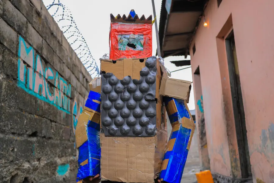 In DRC’s capital city of Kinshasa, Peggy, 16, collects cardboard boxes littered throughout her neighborhood to create wearable art that sends a powerful message to her community. In DRC’s capital city of Kinshasa, Peggy, 16, collects cardboard boxes littered throughout her neighborhood to create wearable art that sends a powerful message to her community.