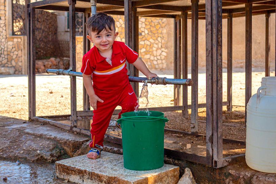 Five-year-old Hasan likes to help out by filling his family's water bucket from the tanks installed by UNICEF near his home in Fafin village, northern rural Aleppo.