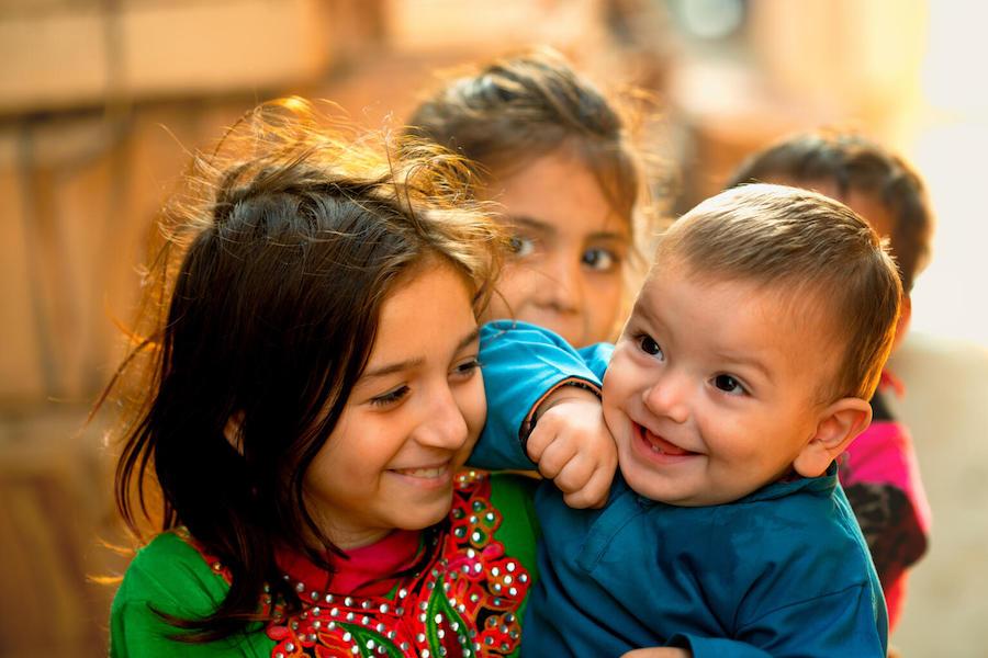 In Lahore, Pakistan in January 2021, a 1-year-old boy and his big sister share a laugh with a UNICEF-supported polio vaccinator.