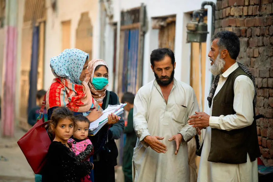 In Lahore, Pakistan, polio community workers Shamsa and Sabiha (first and second from left behind the children) encourage fathers to make sure their all children are immunized against polio. In Lahore, Pakistan, polio community workers Shamsa and Sabiha (first and second from left behind the children) encourage fathers to make sure their all children are immunized against polio.