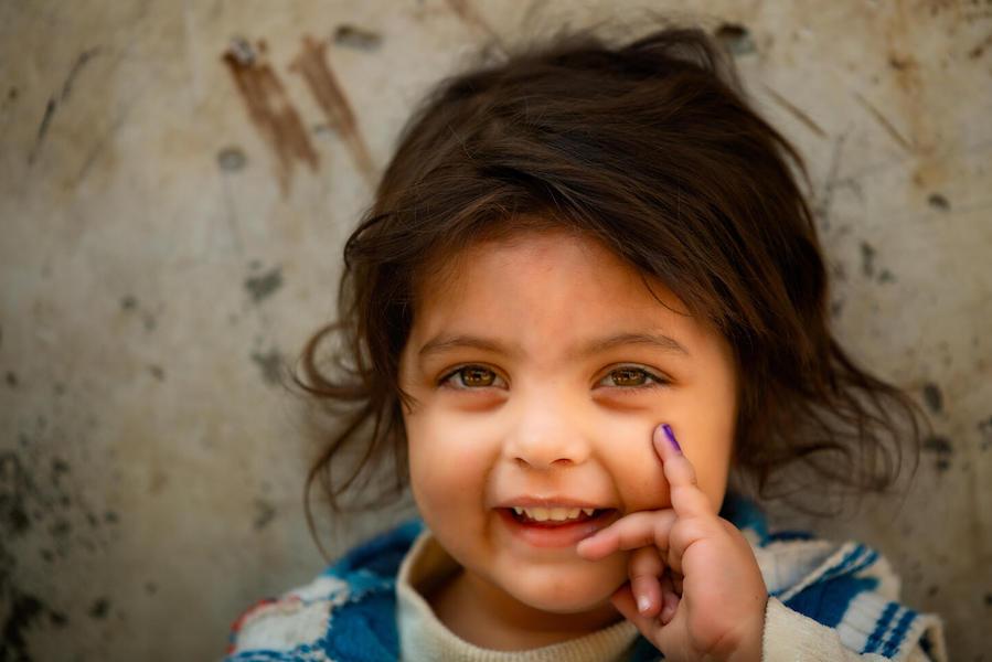 In Lahore, Pakistan in January 2021, a 3-year-old girl shows her finger, marked in purple to indicate she has been vaccinated against polio.