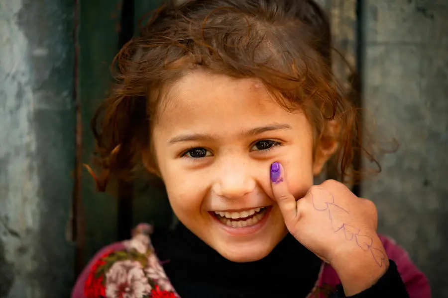 In Lahore, Pakistan, a 4-year old-girl smiles for the UNICEF camera showing her marked finger after receiving the polio vaccine.